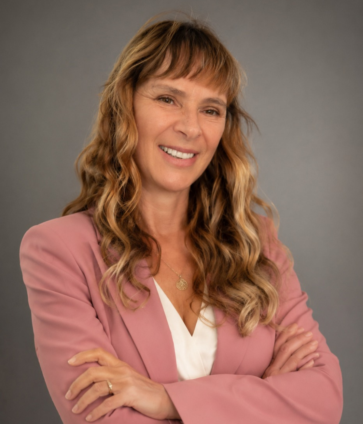 Retrato de Débora Dubay, especialista em Gestão Emocional, sorrindo de braços cruzados.